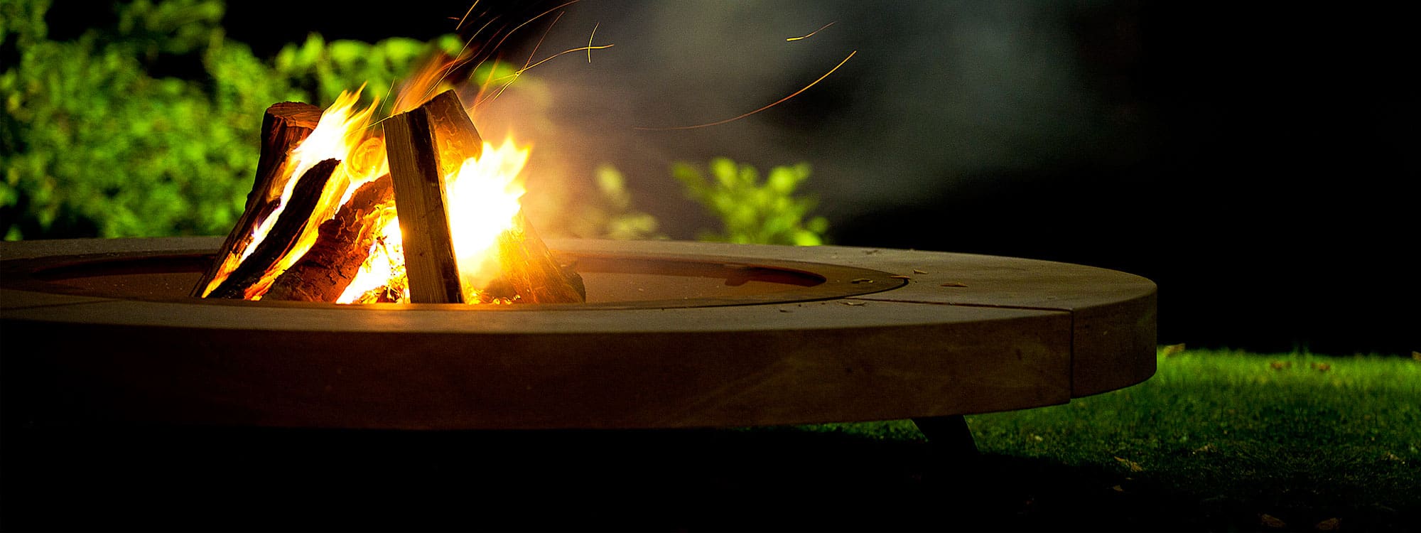 Nighttime image of roaring flames within Rondo fire pit by AK47 Design