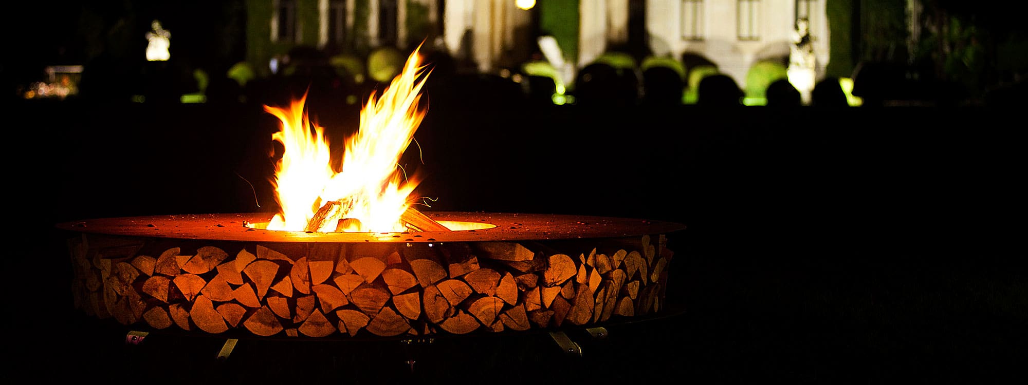 Image of AK47 Zero round fire pit in corten steel with flames blazing from combustion chamber