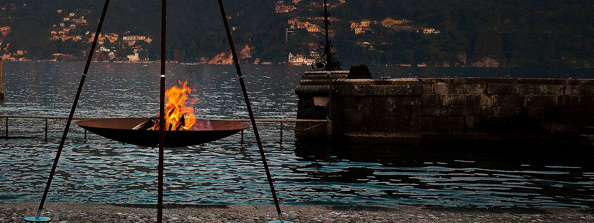 Image of AK47 Tripee tripod fire bowl ablaze on the shores of Lake Como, Italy.