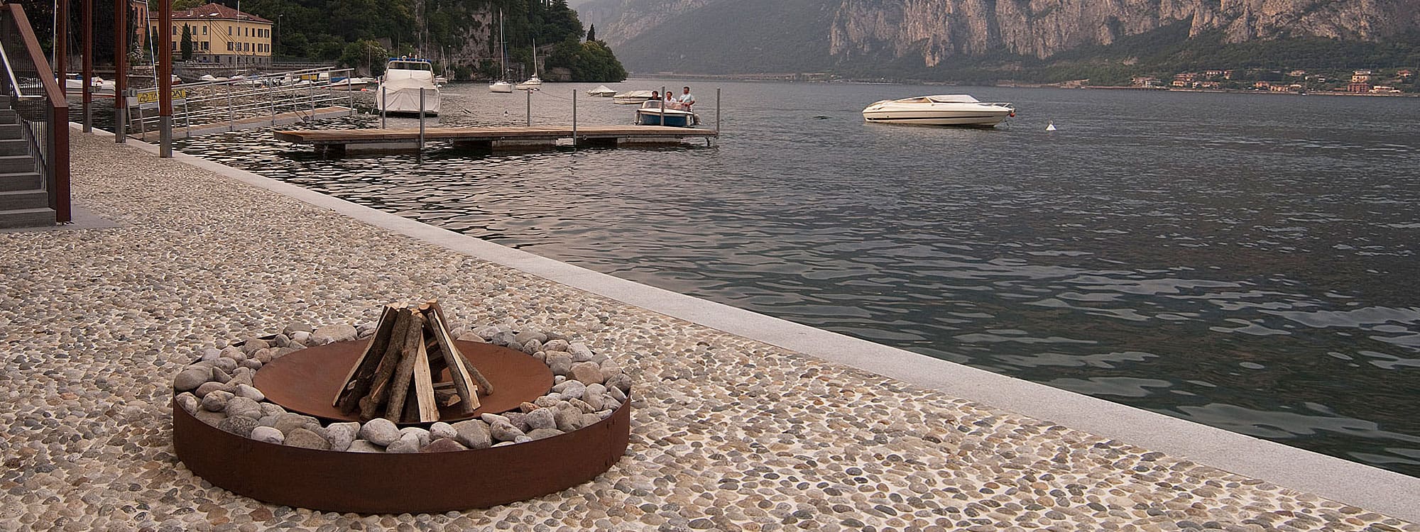 Image of AK47 Zen fire pit on shores of Lake Como and speedboats in background