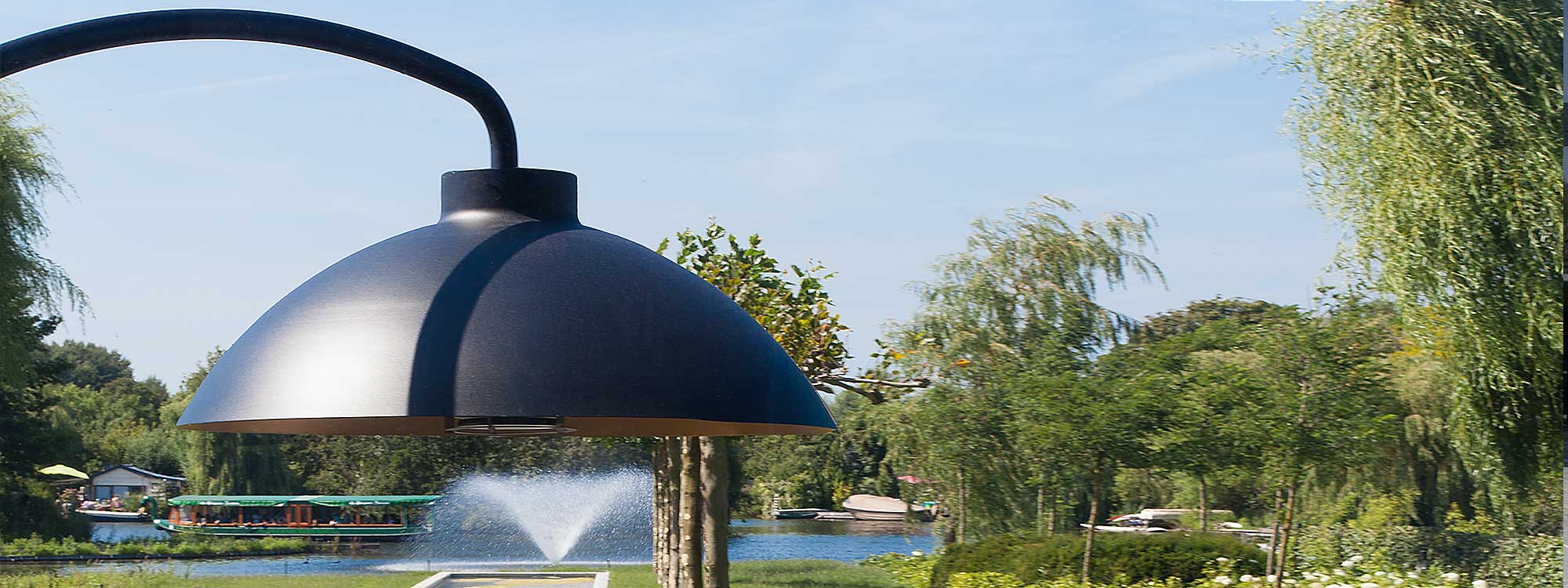 Image of black hood of Heatsail Dome heater on summer's day with canal boats and trees in background