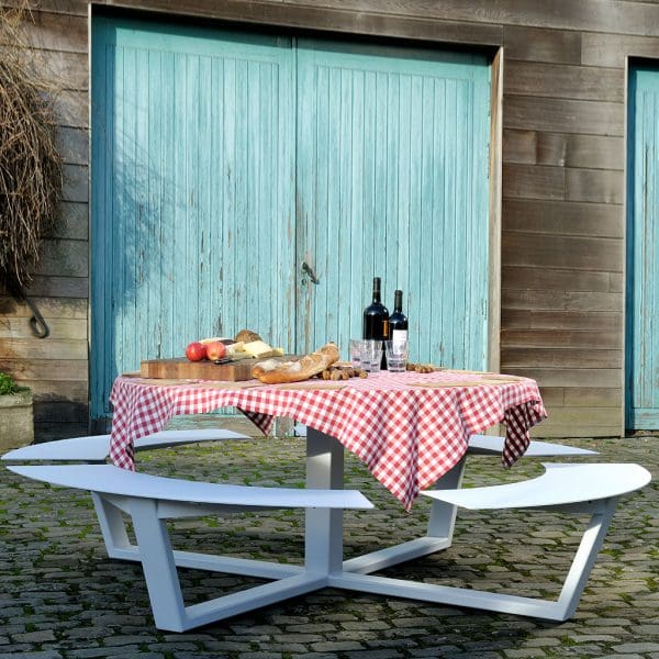 Image of La Grande Ronde modern round picnic table in white shown in cobbled courtyard