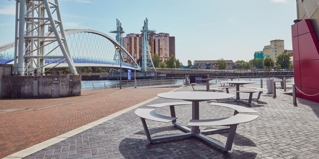 Image of a pair of La Grande Ronde round picnic tables outside thew Lowry Gallery at Salford Quays, Manchester