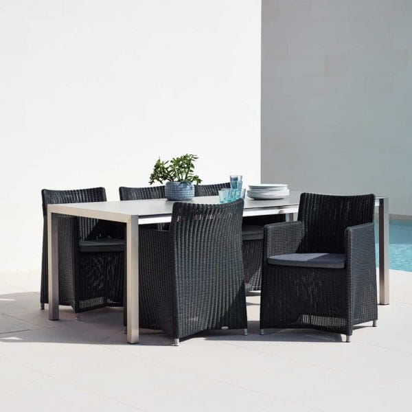 Image of Cane-line Diamond garden chairs in black rattan weave around a stainless steel dining table