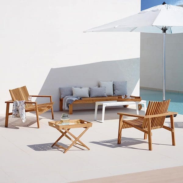 Image of Cane-line Amaze teak lounge set in sunny courtyard next to swimming pool