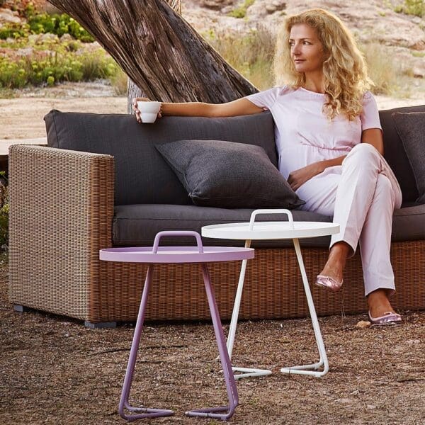 Image of woman sat on natural rattan Chester garden sofa with taupe outdoor cushions by Cane-line