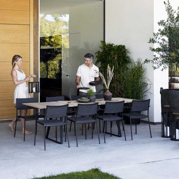 Image of couple around Cane-line Less garden chairs and Copenhagen table in lava-grey with teak table top