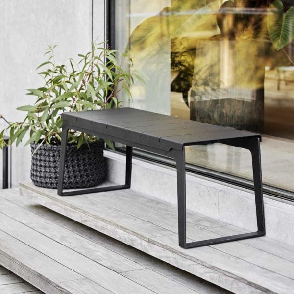 Image of dark grey Copenhagen garden bench by Caneline, shown on decked steps outdoors.