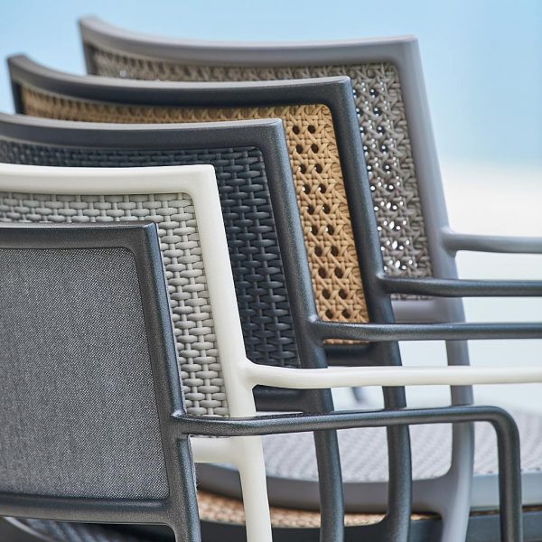 Image of detail of backs of stacked Less modern garden chairs by Cane-line, shown in a range of different color finishes