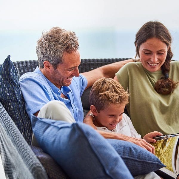 Image of 2 adults and a child relaxing on Mega garden daybed by Cane-line