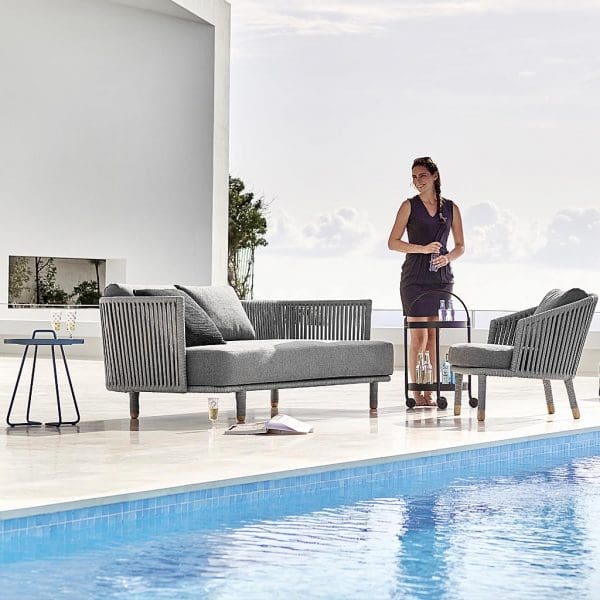 Image of woman stood on poolside next to Moments garden sofa and lounge chair by Cane-line