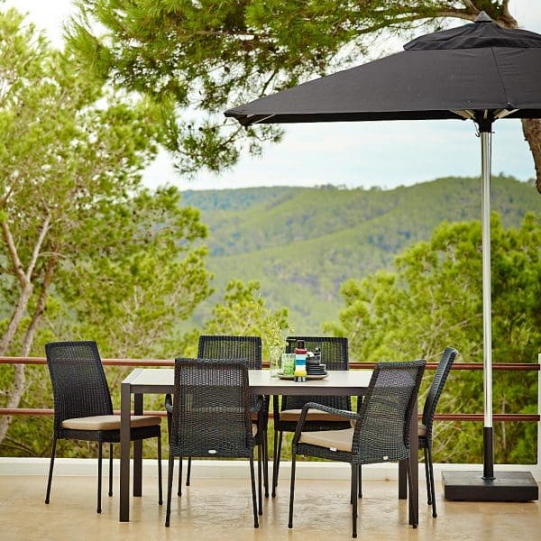 Image of Newport black garden chairs and Cane-line dining table with trees and hills in background