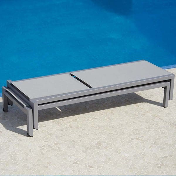 Image of pair of stacked light-grey Relax modern sunbeds on poolside by Cane-line.