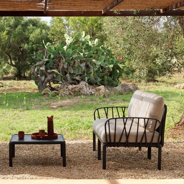 Image of Komodo anthracite garden sofa and low table on wood chip floor beneath split cane pergola with cactuses in the background