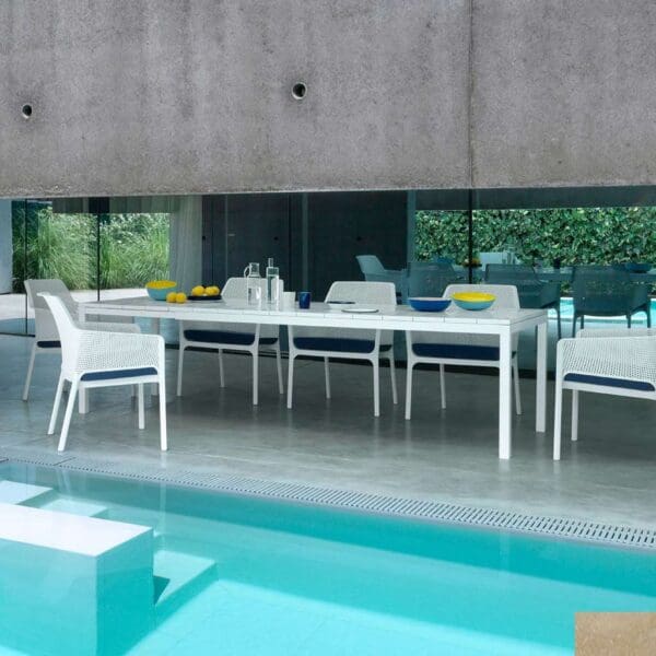 Image of Net white garden armchairs and Rio white garden able on minimalist terrace with inviting swimming pool in the foreground