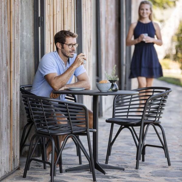 Image of man sat on black Blend aluminium garden chair by Cane-line