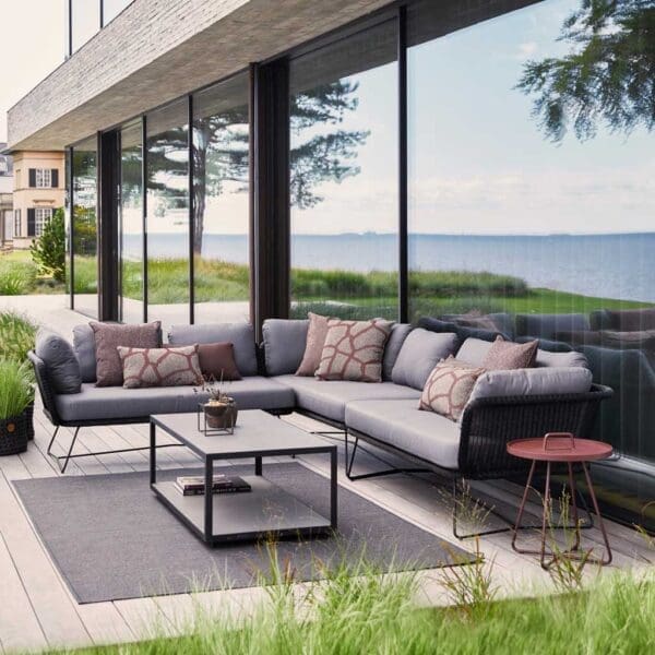 Image of black rattan corner sofa with grey cushions and rectangular coffee table by Caneline