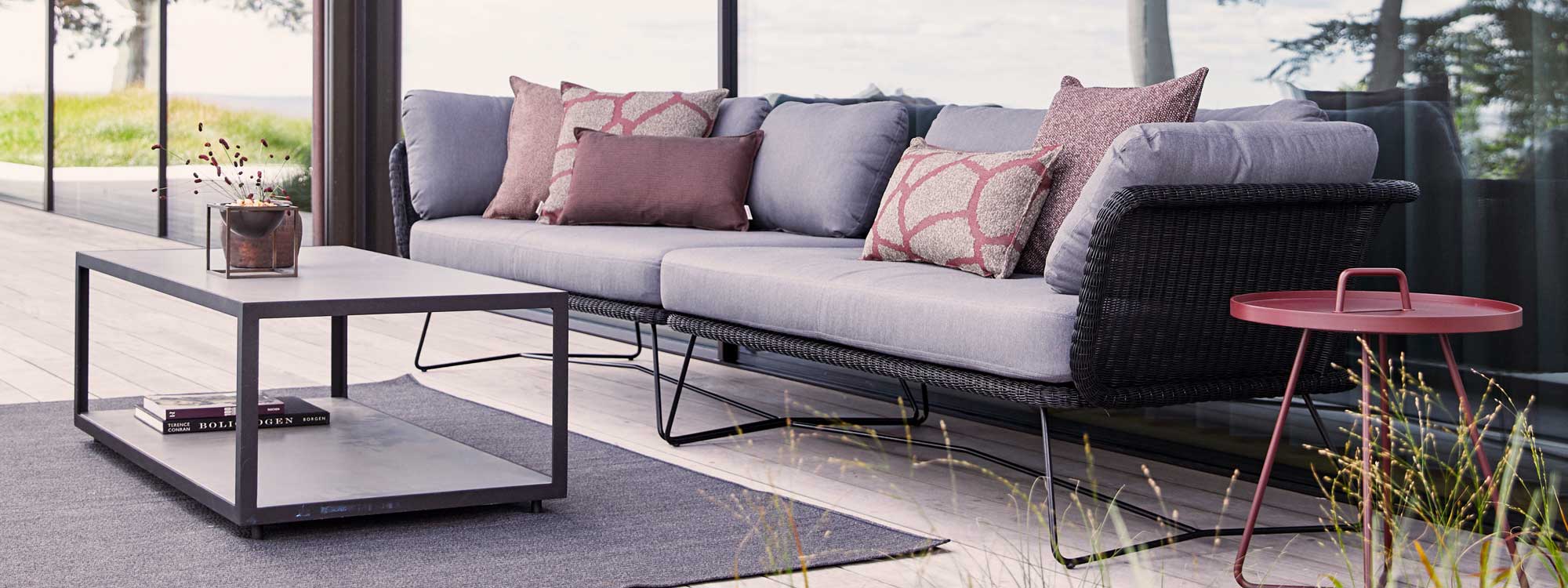 Image of Caneline Horizon black rattan garden sofa with grey cushions, with lava-grey Level table with ceramic surfaces