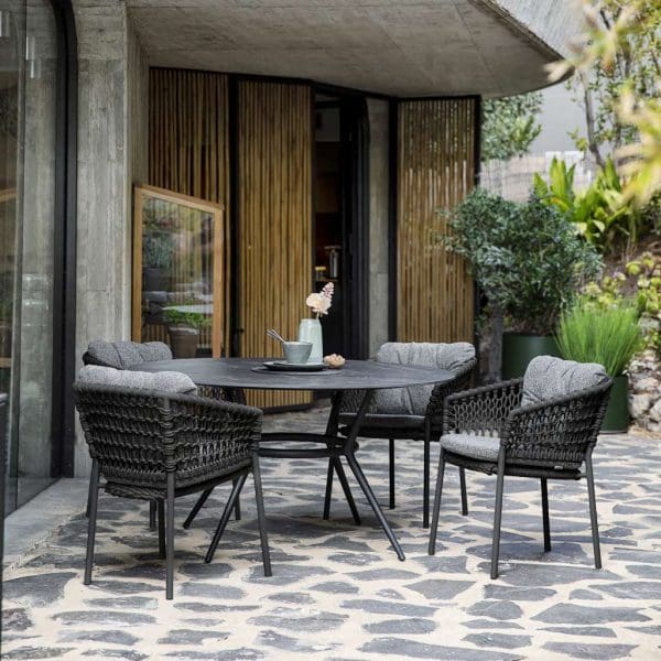 Image of Joy lava grey garden table with black Fossil ceramic top and Ocean garden chairs with plump cushions by Cane-line