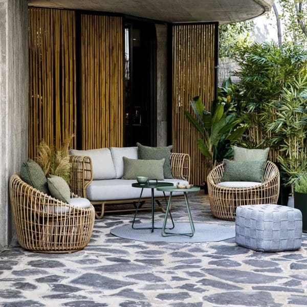 Image of outdoor terrace with Caneline Nest 2 seat sofa and round Nest lounge chairs, shown in natural Cane-line Weave with Taupe cushions