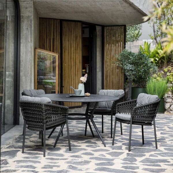 Image of 4 dark grey Ocean armchairs with snug grey cushions around Joy round garden table by Caneline