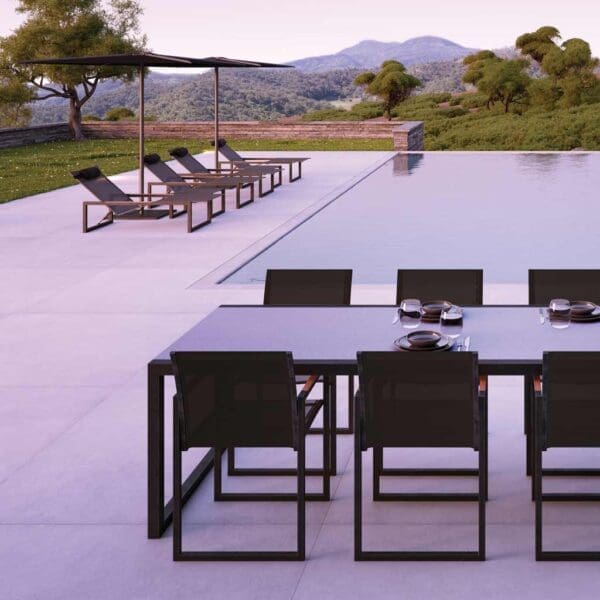 Royal Botania Ninix garden furniture & Oazz parasols shown around a tranquil horizon swimming pool at dusk