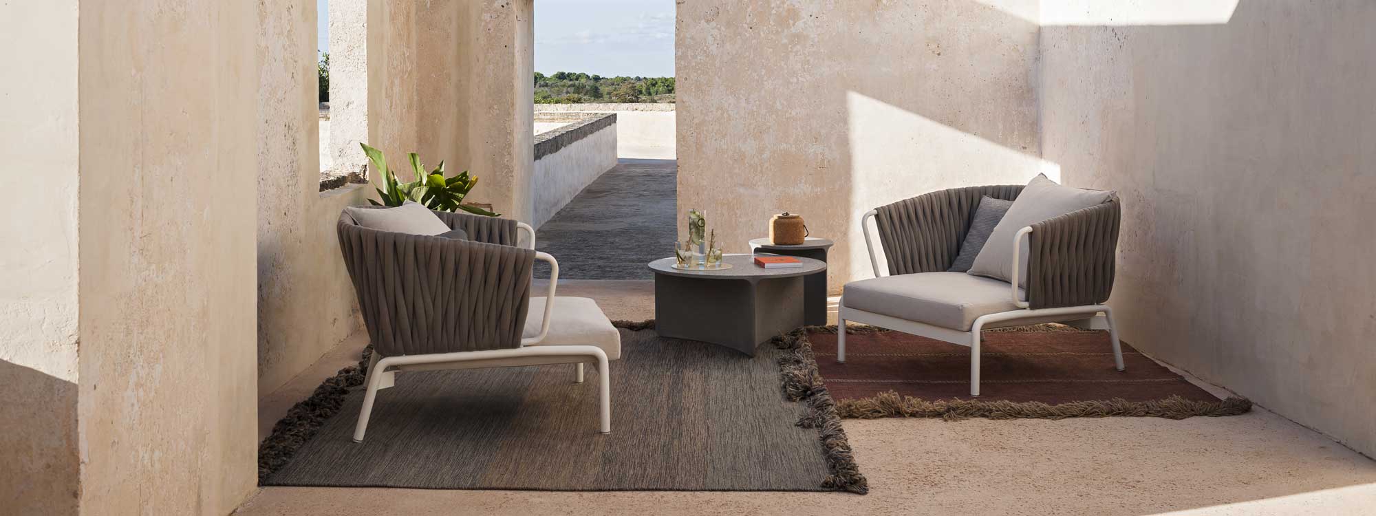 Image of pair of RODA Spool lounge chairs with Sand-coloured padded belt backs and taupe seat cushions together with Aspic low table