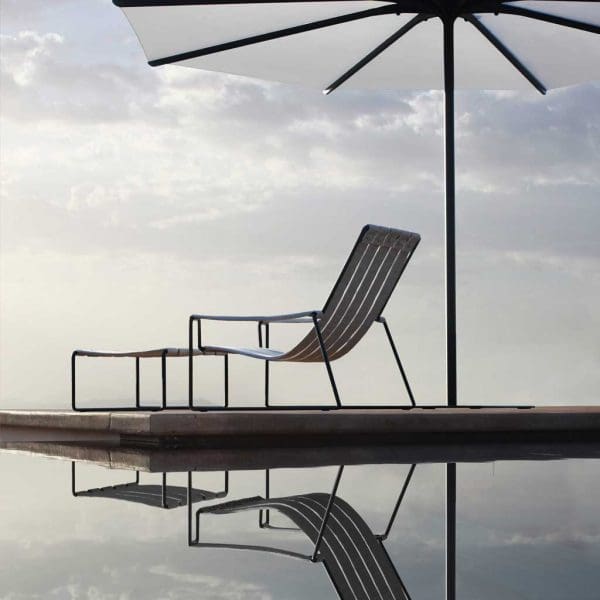 Silhouette of Royal Botania Strappy garden chair & Oazz modern parasol with reflection cast in the swimming pool beneath
