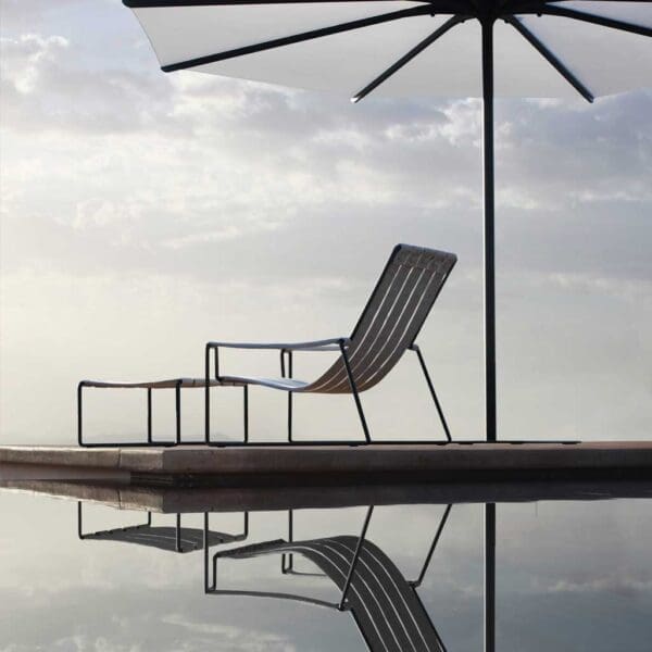 Silhouette of Royal Botania Strappy garden chair & Oazz modern parasol with reflection cast in the swimming pool beneath