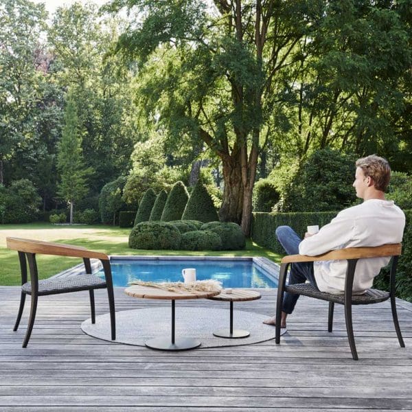 Image of man sat in Royal Botania Jive chair in front of swimming pool