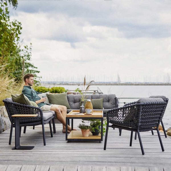 Image of man drinking a coffee sat on Ocean garden sofa by Caneline Danish outdoor furniture
