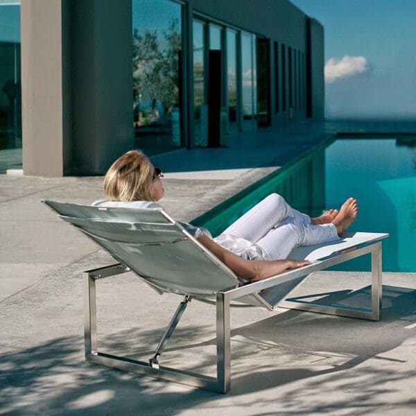 Image of woman reclining in Ninix stainless steel lounge bed by Royal Botania outdoor furniture