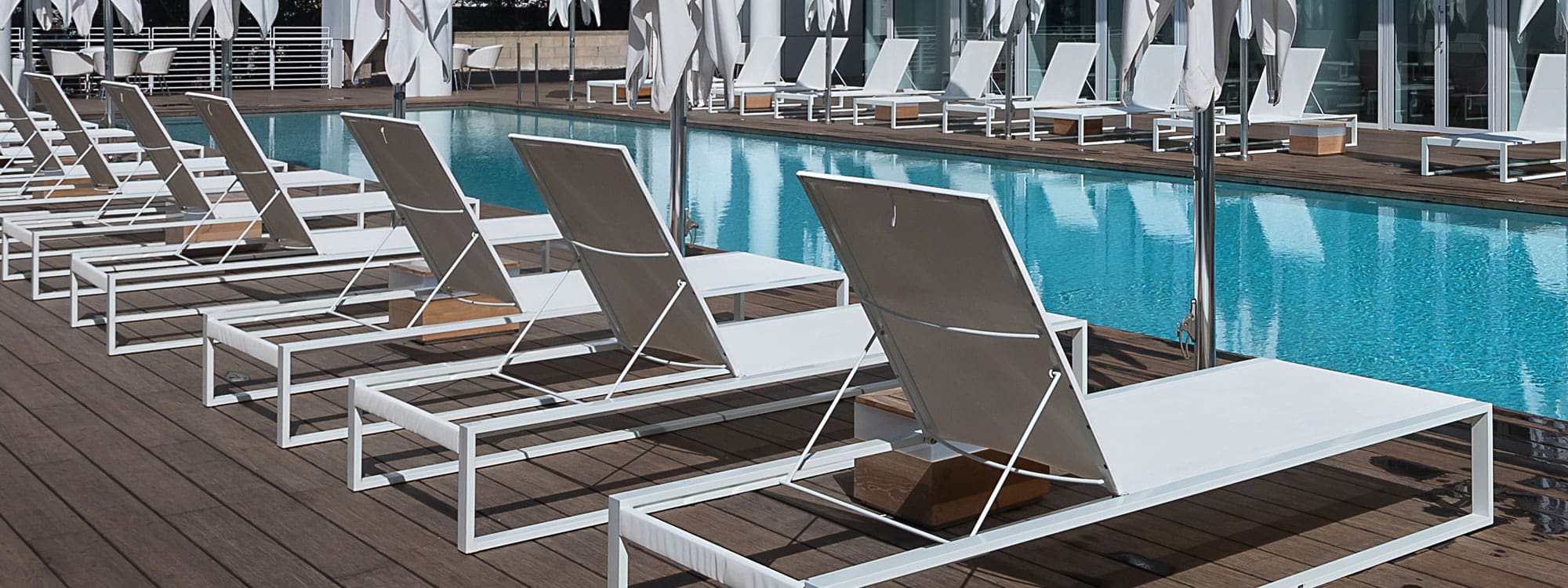 Image of hotel swimming pool with rows of Siesta modern sun loungers by FueraDentro on both sides
