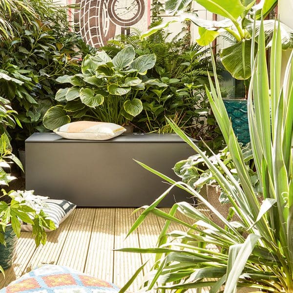 Image of El Pecho modern garden storage chest in grey HPL, shown surrounded by exotic plants