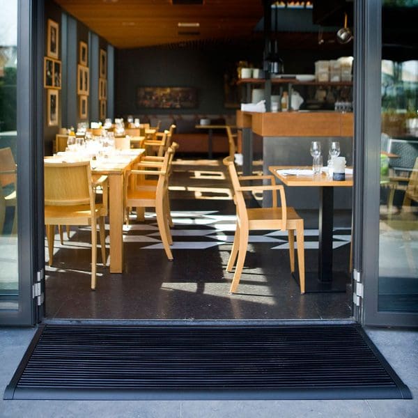 Image of RiZZ The New Standard contemporary door mat in anthracite aluminium, shown outside restaurant doorway