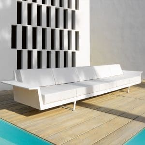 Image of Vondom Delta white garden sofa on decked poolside with unusual architectural wall feature in the background