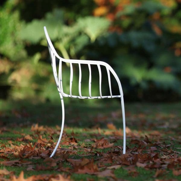 Image of side view of white Folia chair by Royal Botania sat in fallen leaves on lawn