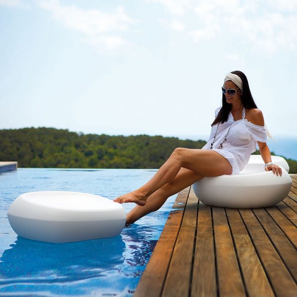 Image of woman dipping her toes into swimming pool whilst sat on Vondom Moma low pouf