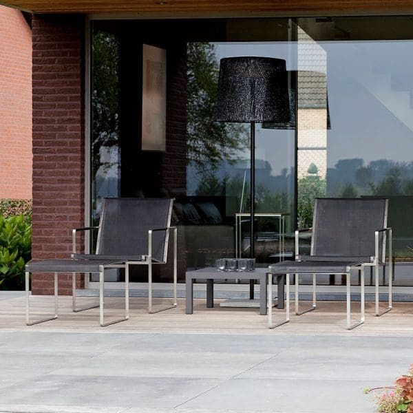 Image of pair of FueraDentro Poltrona garden easy chairs and foot rests on covered outdoor terrace