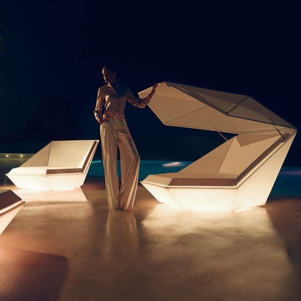 Nighttime image of woman stood next to Vondom Faz illuminated white garden daybed