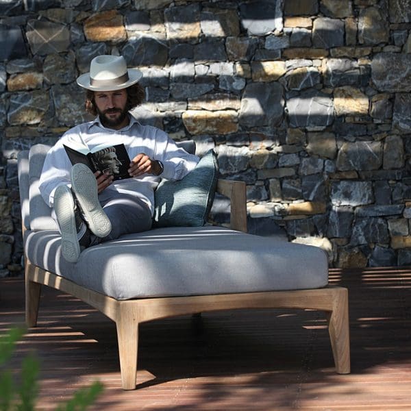 Image of Man in Panama hat reading book on Zenhit teak chaise longue by Royal Botania