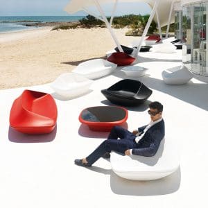 Image of dude in suit and sunglasses sat in Vondom UFO futuristic white garden chair, surrounded by red and white UFO furniture on white terrace by seaside