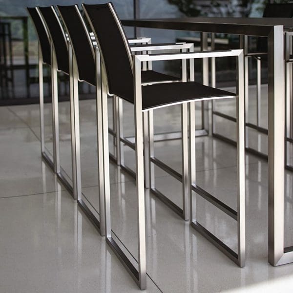 Image of Royal Botania Ninix bar table and bar stools with electro-polished stainless steel frame and black surfaces on minimalist terrace