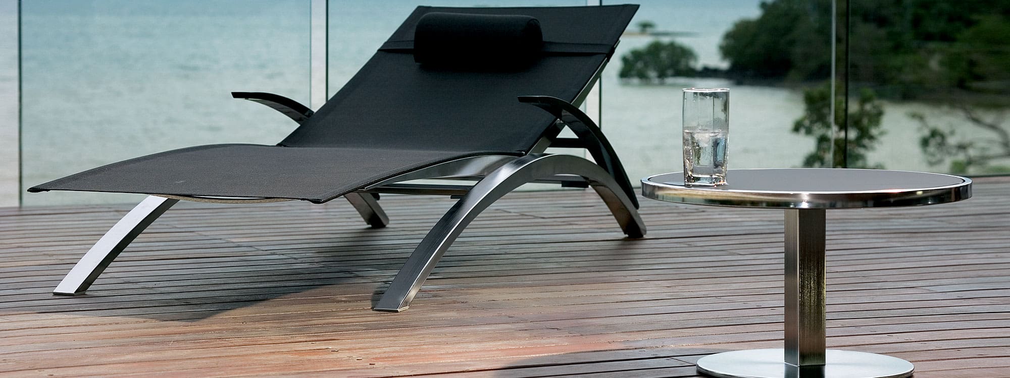 Image of Royal Botania O-ZON sun lounger and size table with shiny stainless steel frames and black surfaces
