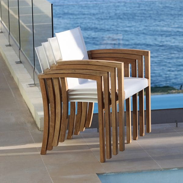 Image of stacked XQI 55 teak carver chairs with white seat & back by Royal Botania