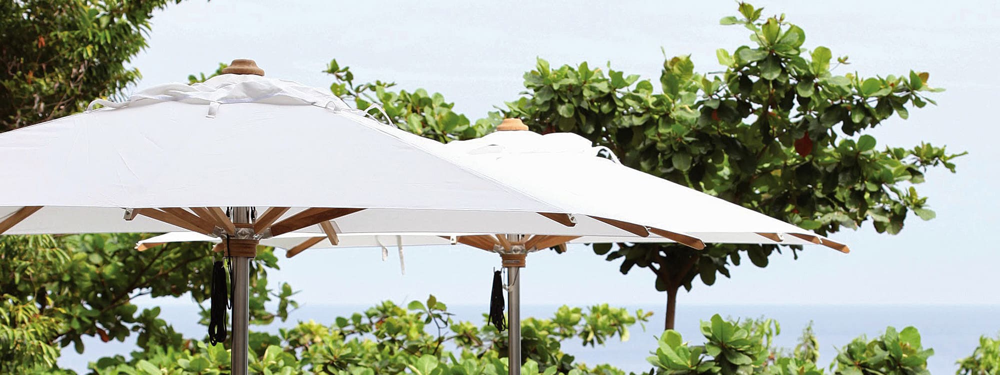 Image of pair of Shady parasols with white canopies and teak masts by Royal Botania