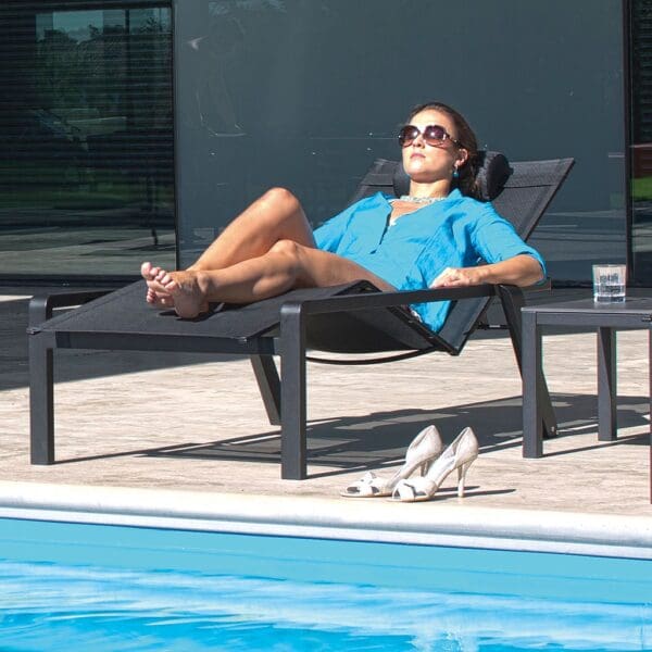 Image of woman snoozing in black Alura adjustable sunbed by Royal Botania