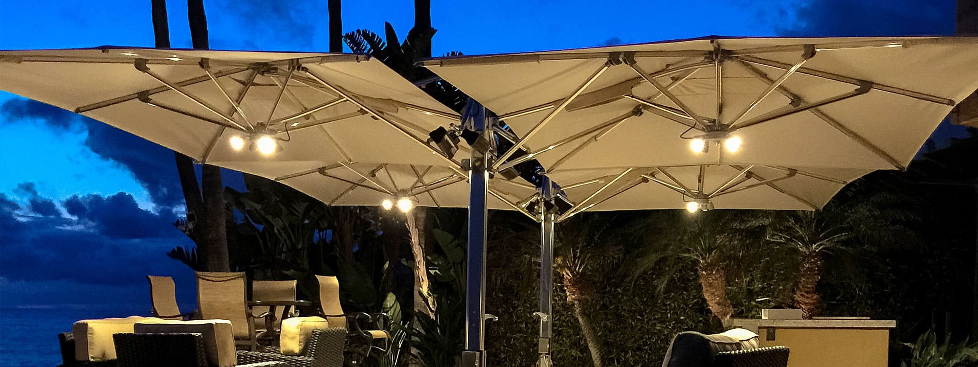 Nighttime image of Tuuci Ocean Master Max Classic Dual cantilever parasols fitted with lights and heating