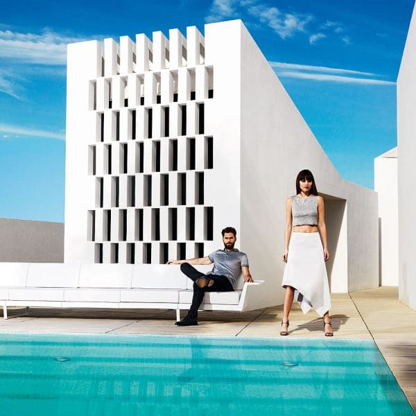 Image of man sat on Vondom Delta long white garden sofa on poolside with woman stood to the side
