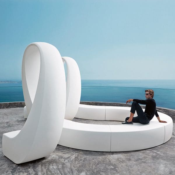 Image of man dressed in black sat on white Vondom AND modular bench with modern spatial design evocative of ampersand
